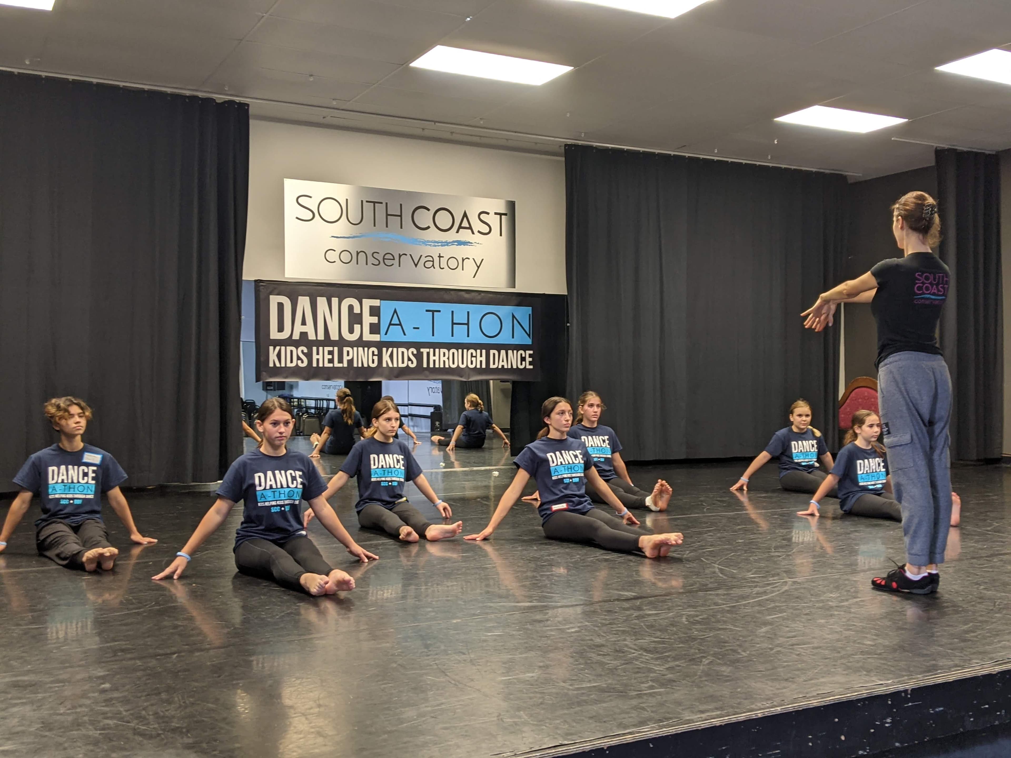 Students rehearsing with an instructor beneath a Dance-A-Thon banner