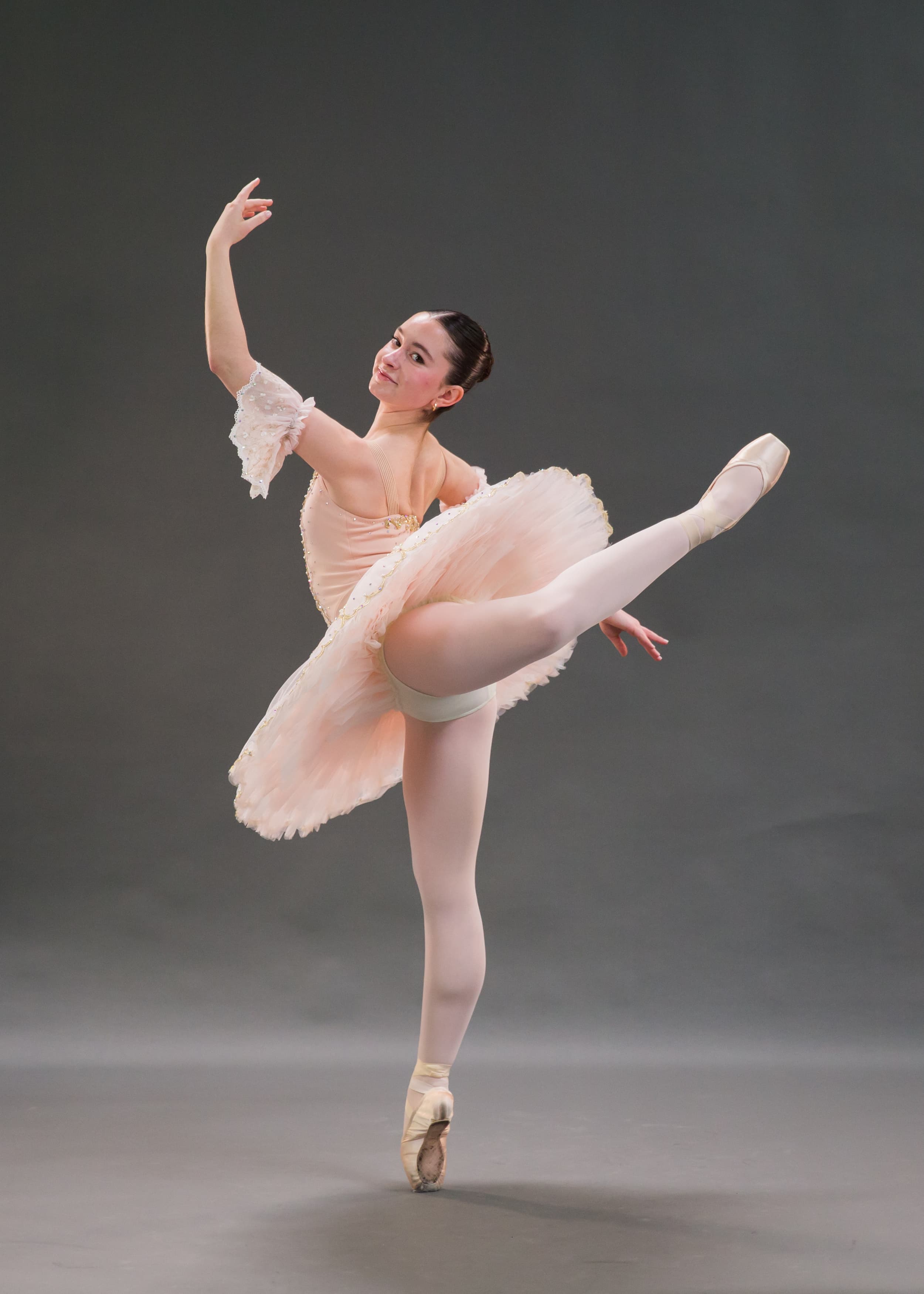 Ballet dancer in a white tutu performing an arabesque