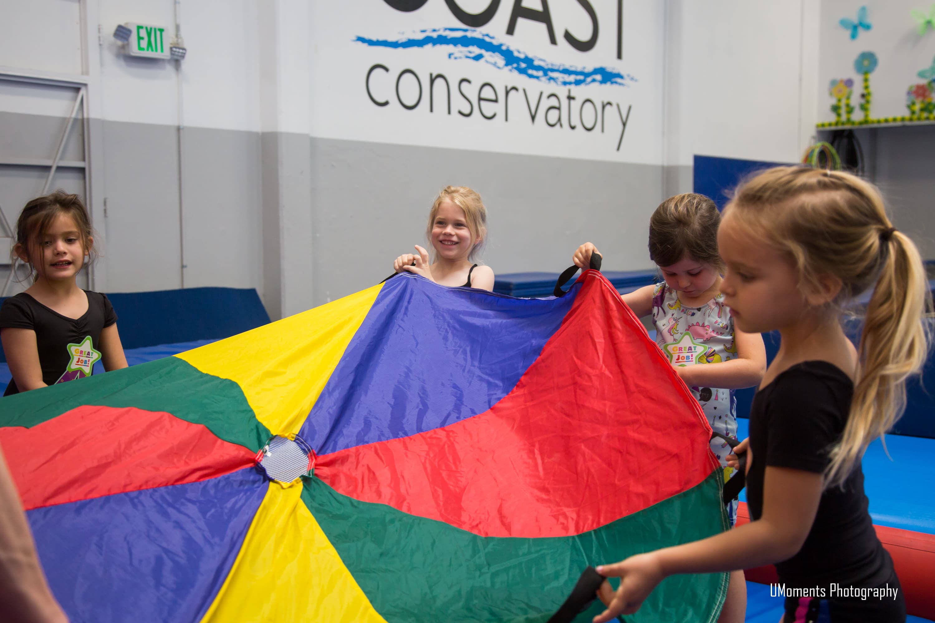 Children playing with a colorful parachute in a movement class